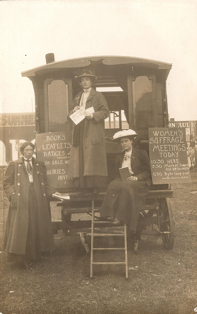 Three suffragettes standing by a caravan at Bridlington