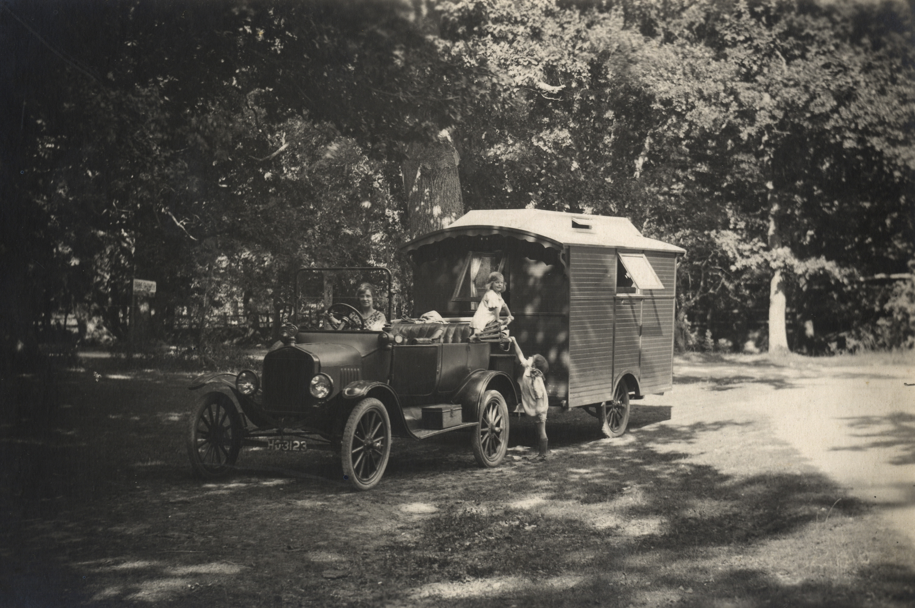 Woman driving a 1921 Ford Model T towing a caravan with two children